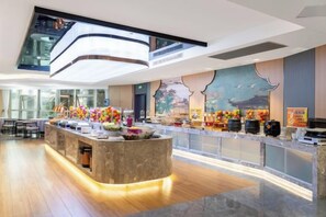 Een moderne hotelentree met een centraal gelegen receptiebalie, een groot raam en een hoge plafond.