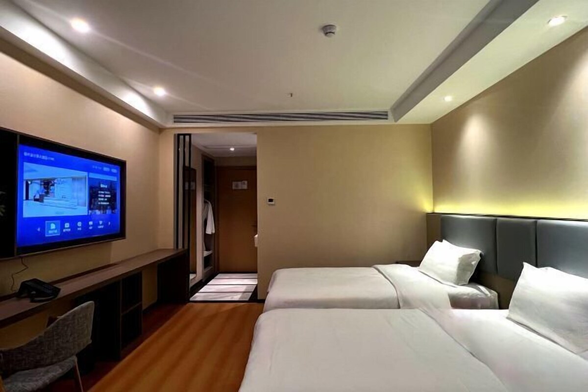 Une chambre d’hôtel avec deux lits, un téléviseur fixé au mur, un bureau et une chaise.