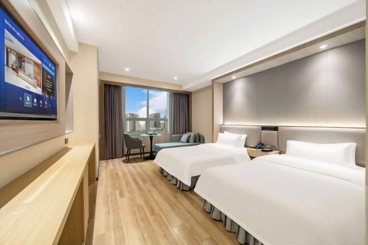 Une chambre d’hôtel avec deux lits, un bureau et une télévision.