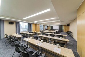 Une salle de conférence équipée de plusieurs tables et chaises, d’un écran de projection et d’une grande fenêtre donnant sur la ville.