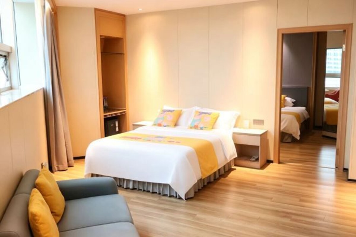 A hotel room with a bed, bedside tables, a sofa, and a wardrobe.