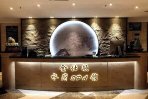 A reception desk with a large illuminated sphere and a wooden counter with neon signage.