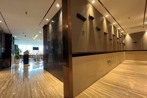 Un hall d’hôtel doté d’un sol en marbre poli, d’un comptoir de réception et d’un espace détente avec des tables et des chaises.
