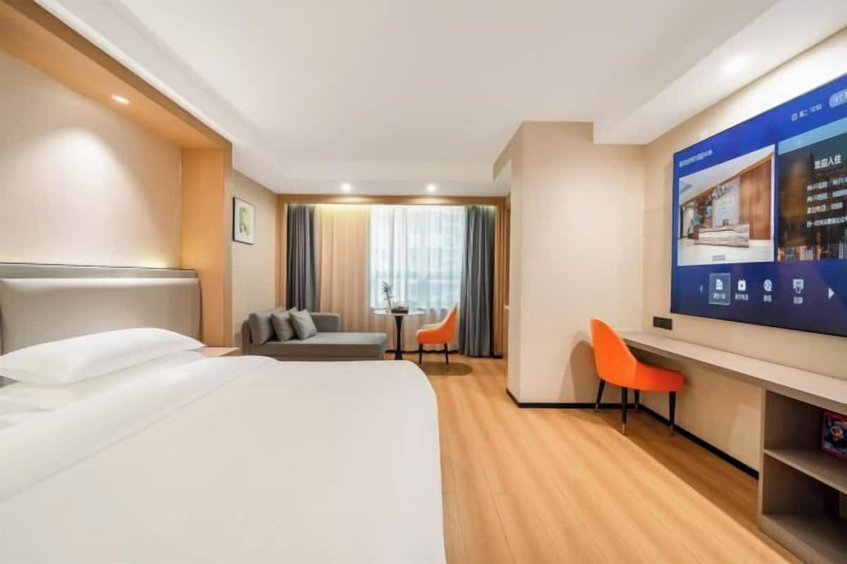 Une chambre d’hôtel avec un lit, un bureau, une chaise et un téléviseur.