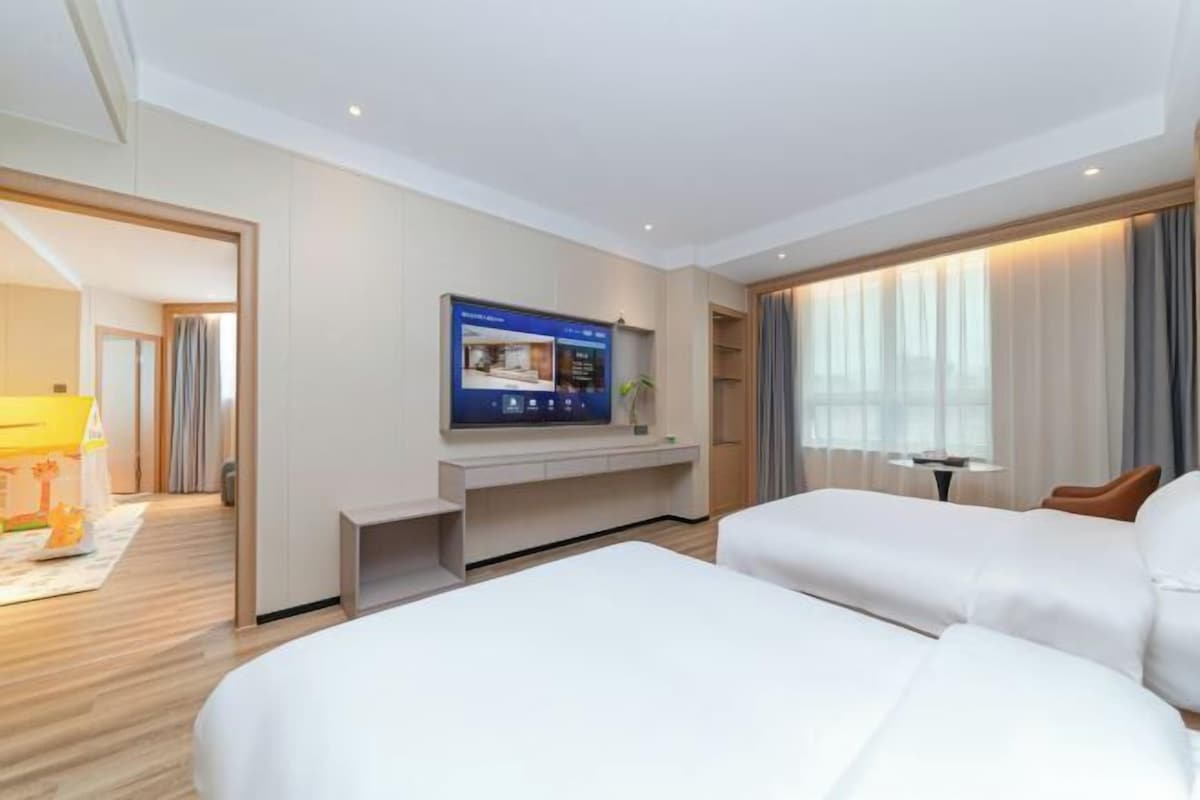 Une chambre d’hôtel avec un grand lit, un téléviseur fixé au mur et un bureau avec une chaise.