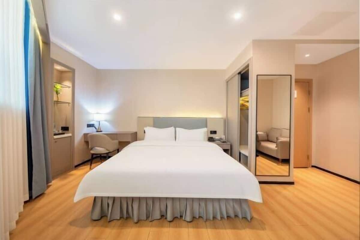Une chambre d’hôtel moderne, dotée d’un grand lit, de tables de chevet, d’un bureau et d’un miroir.