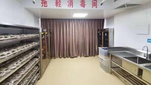 A kitchen with stainless steel appliances, a sink, and shelves with packaged goods. - Overseas Chinese Hotel (Quanzhou)