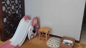 Quarto com área de recreação que inclui um escorrega e um banquinho de madeira.