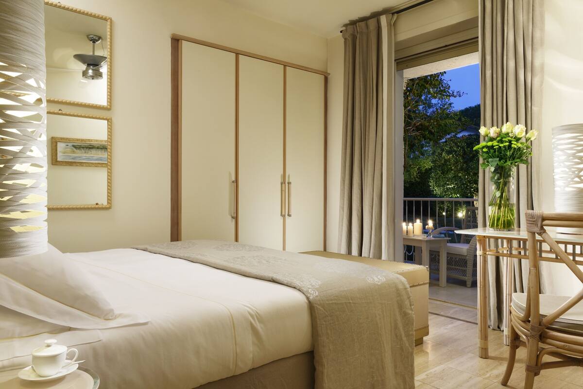 A bedroom with a bed, bedside table, and a view of the balcony.
