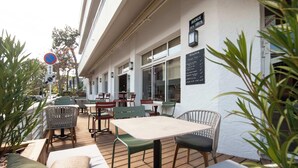 Un espace extérieur aménagé avec des tables et des chaises, un panneau indiquant qu’il est interdit de se garer, et un tableau affichant le menu sur le mur.