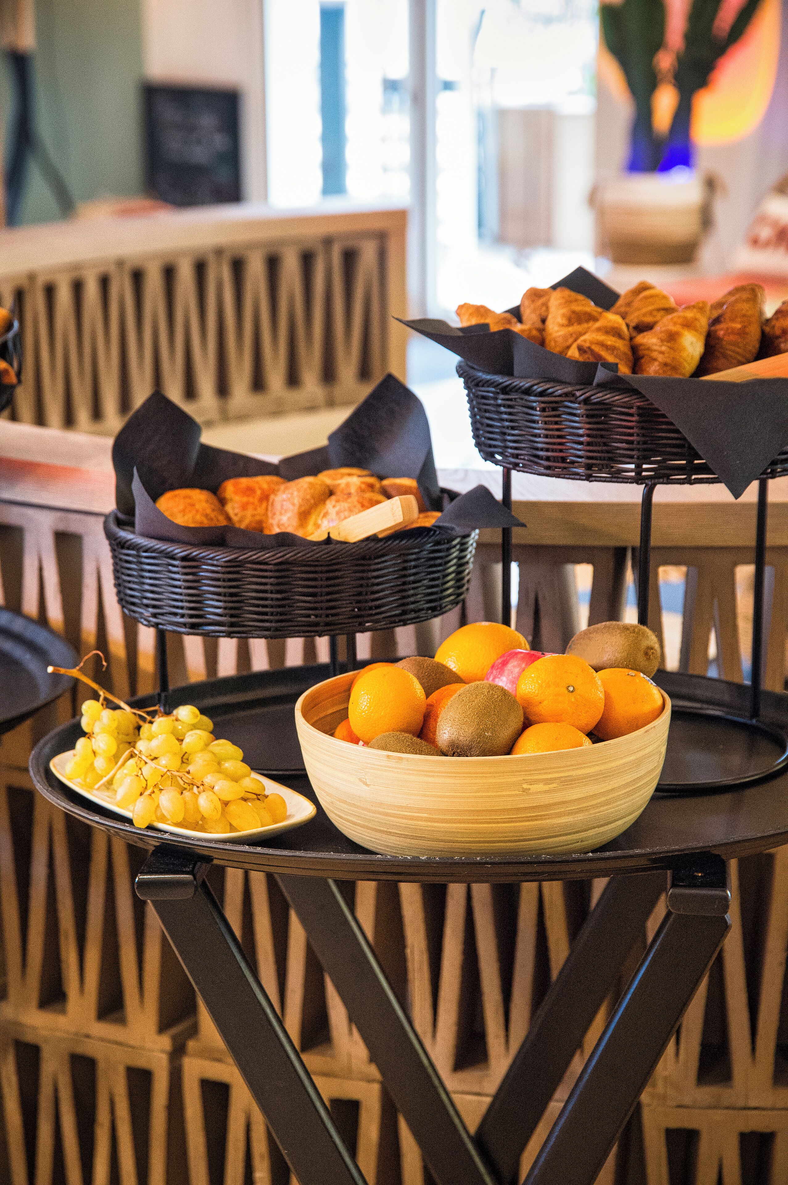 Una mesa con cestas de pan, naranjas y uvas.
