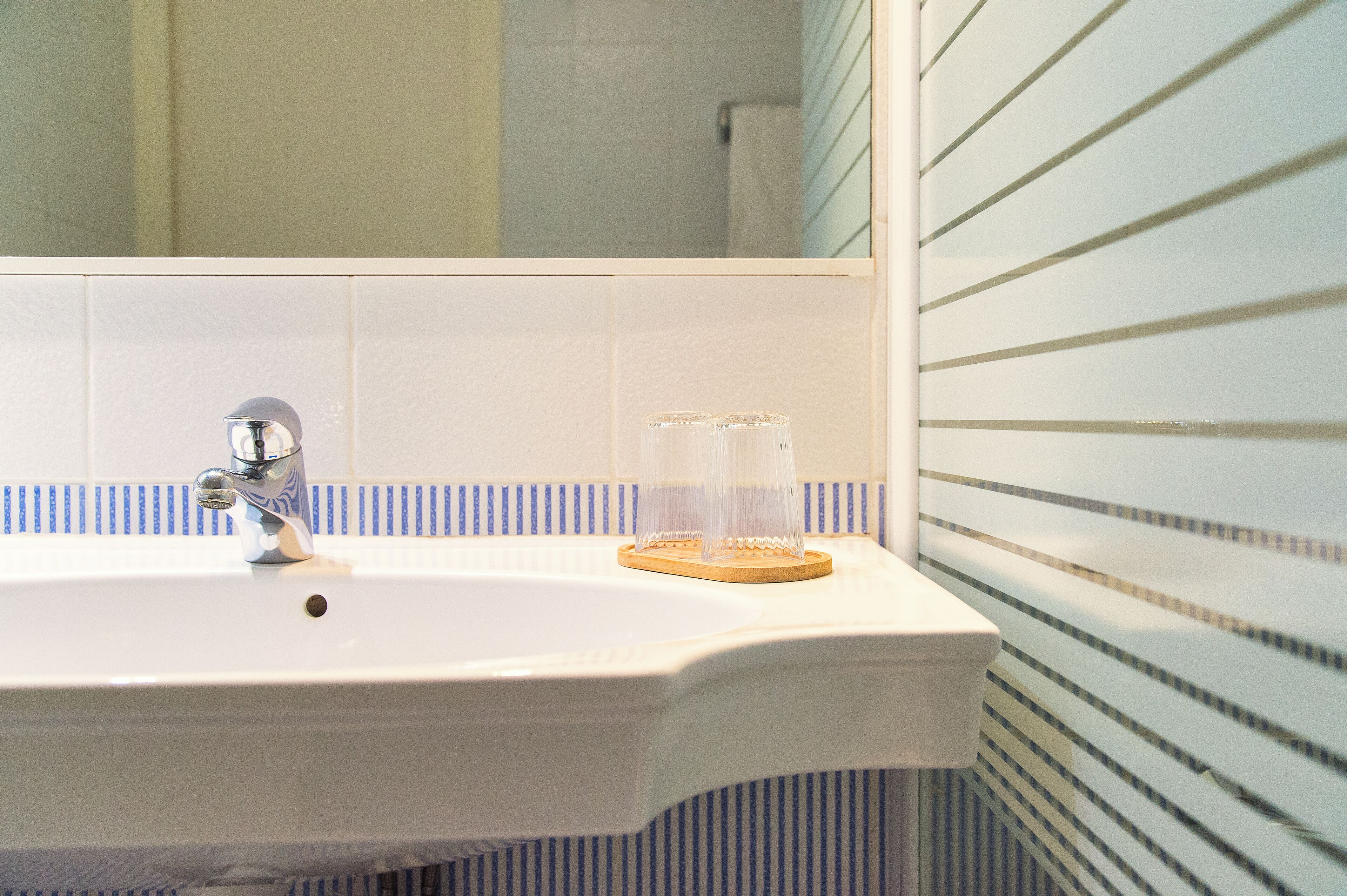 A bathroom with a white sink, a mirror, and a striped wall.