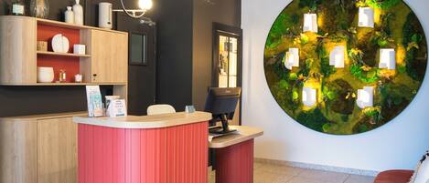 A reception area with a red counter, wooden shelving, and a large circular wall decoration.