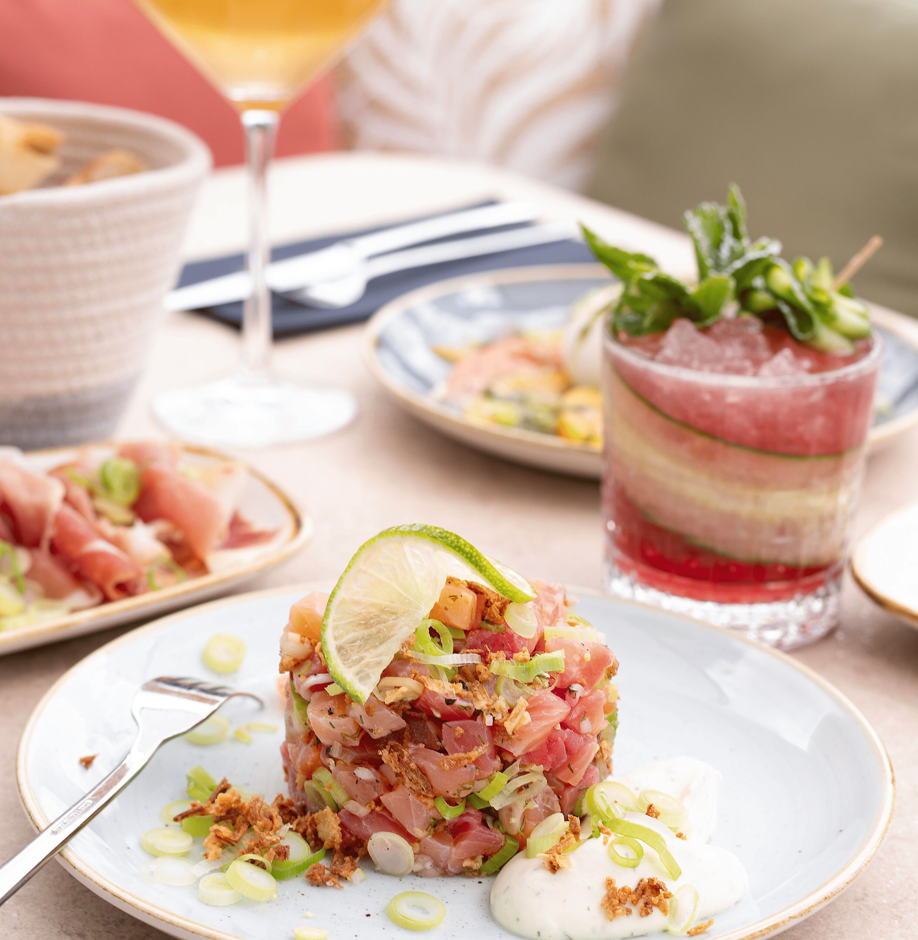 A dining table with a plate of food, a glass of drink, and a bowl.