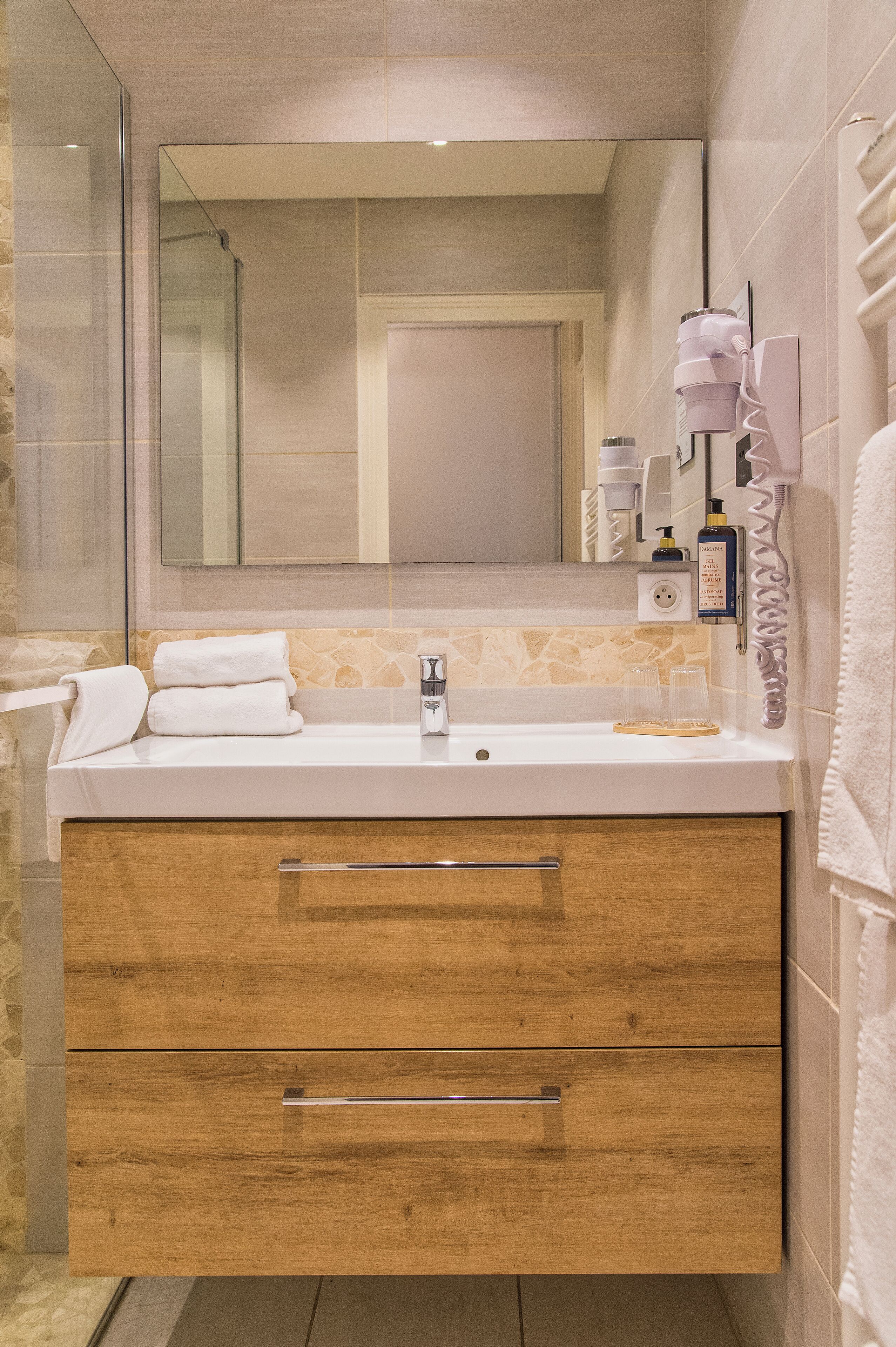 A modern bathroom with a large mirror, a sink, and a vanity with drawers.