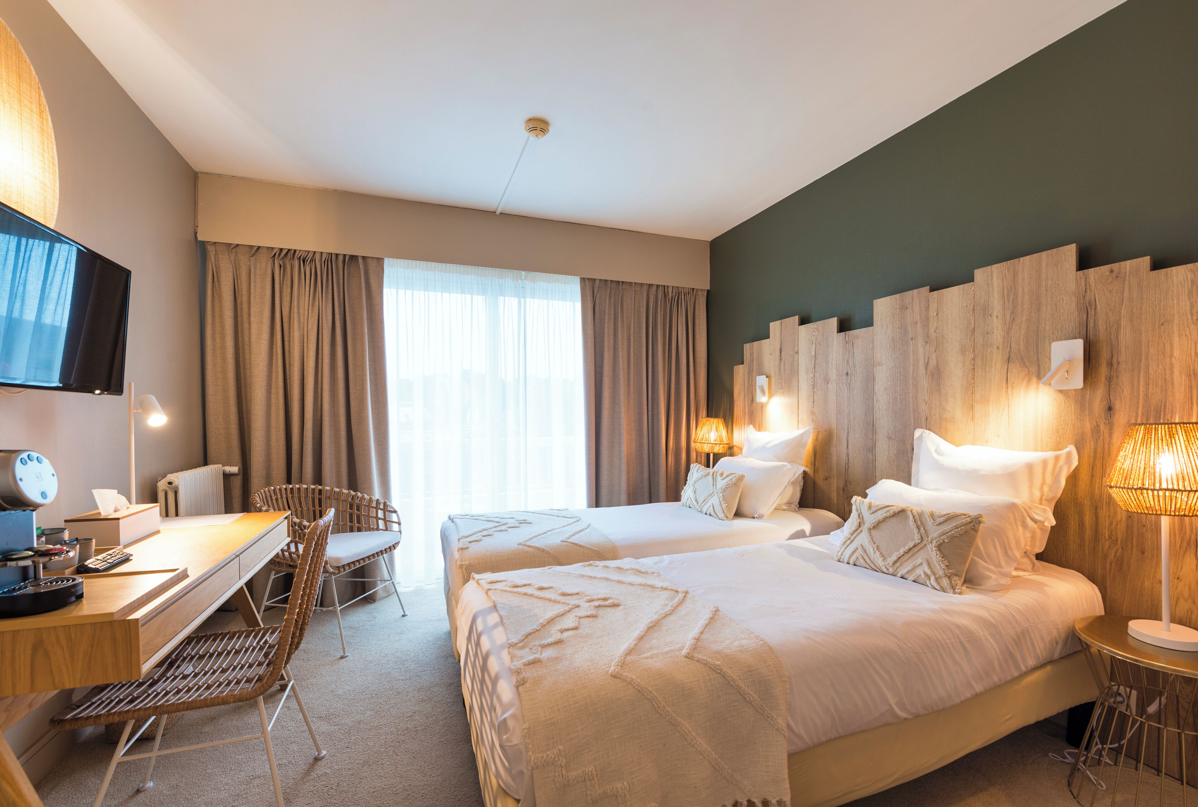 Une chambre d’hôtel avec deux lits, un bureau avec un ordinateur, une chaise et un téléviseur.