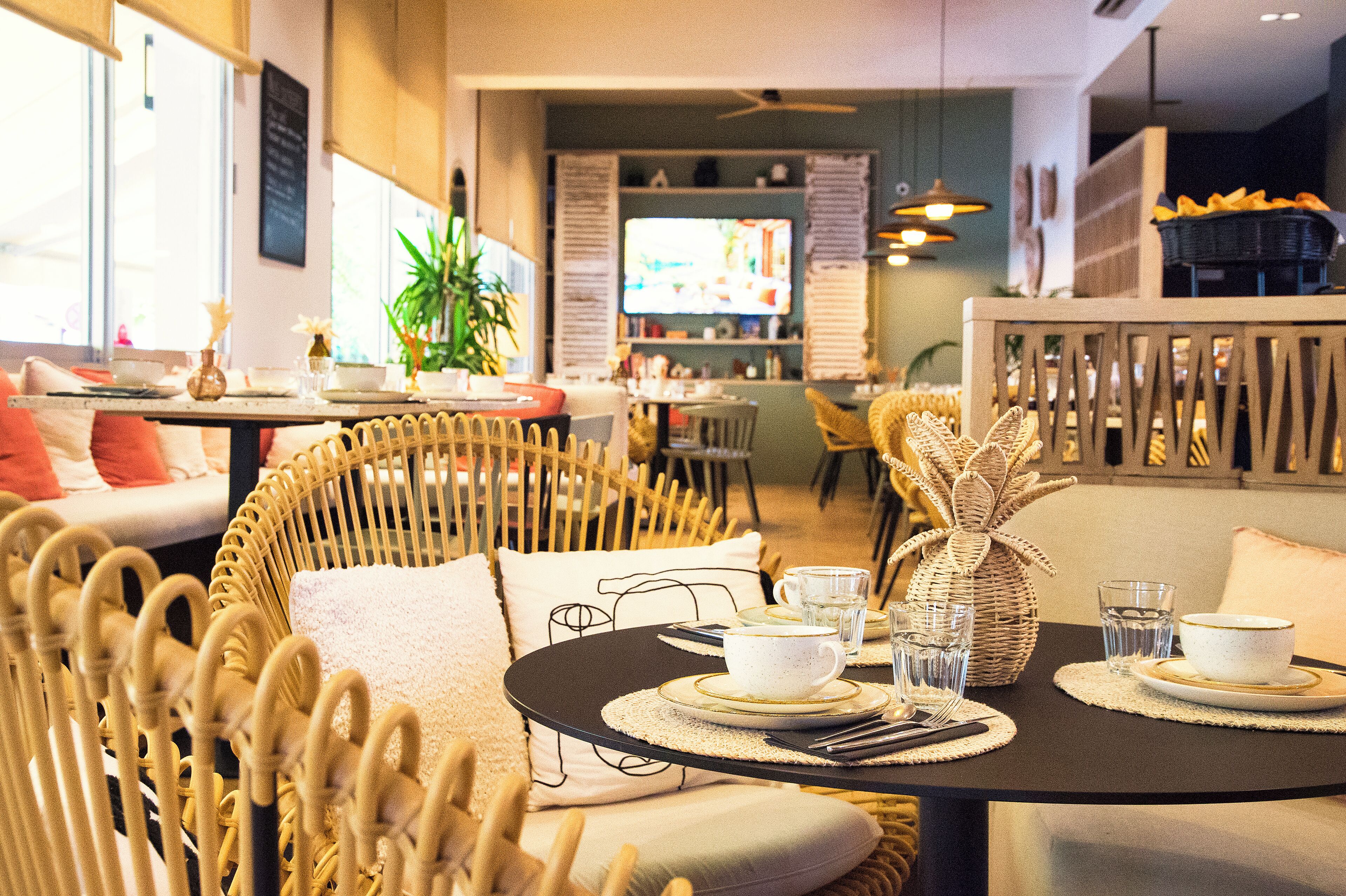 A cozy restaurant with wicker furniture, a television in the background, and a buffet area.