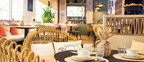 A cozy restaurant with wicker furniture, a television in the background, and a buffet area.