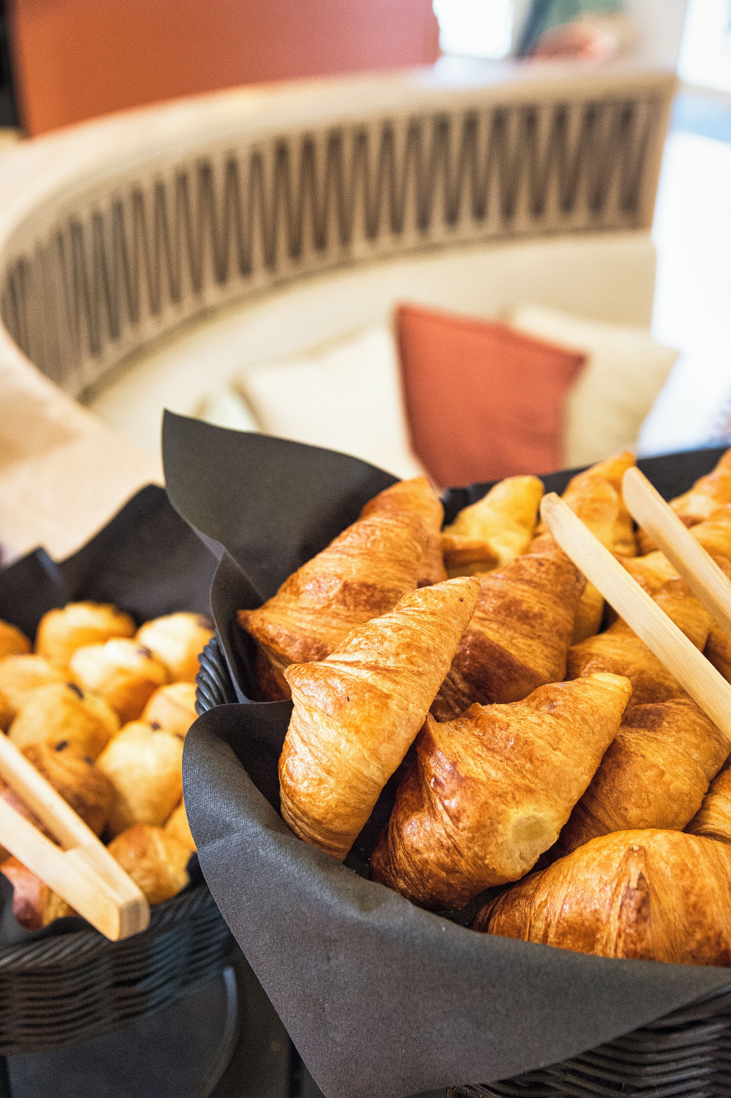 A basket of assorted pastries, including croissants and other baked goods, likely available for breakfast or snacks.