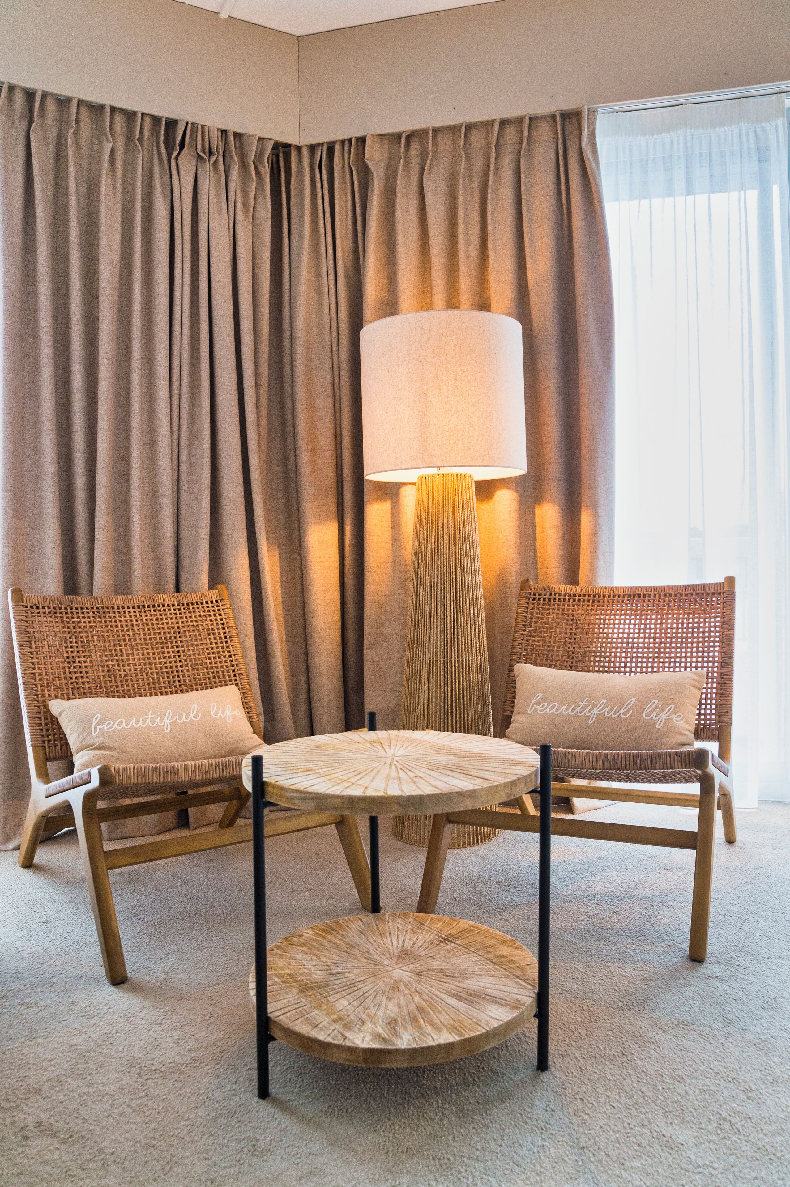 A room with two wicker chairs, a round table, and a floor lamp.
