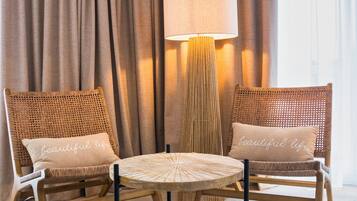 A room with two wicker chairs, a round table, and a floor lamp.