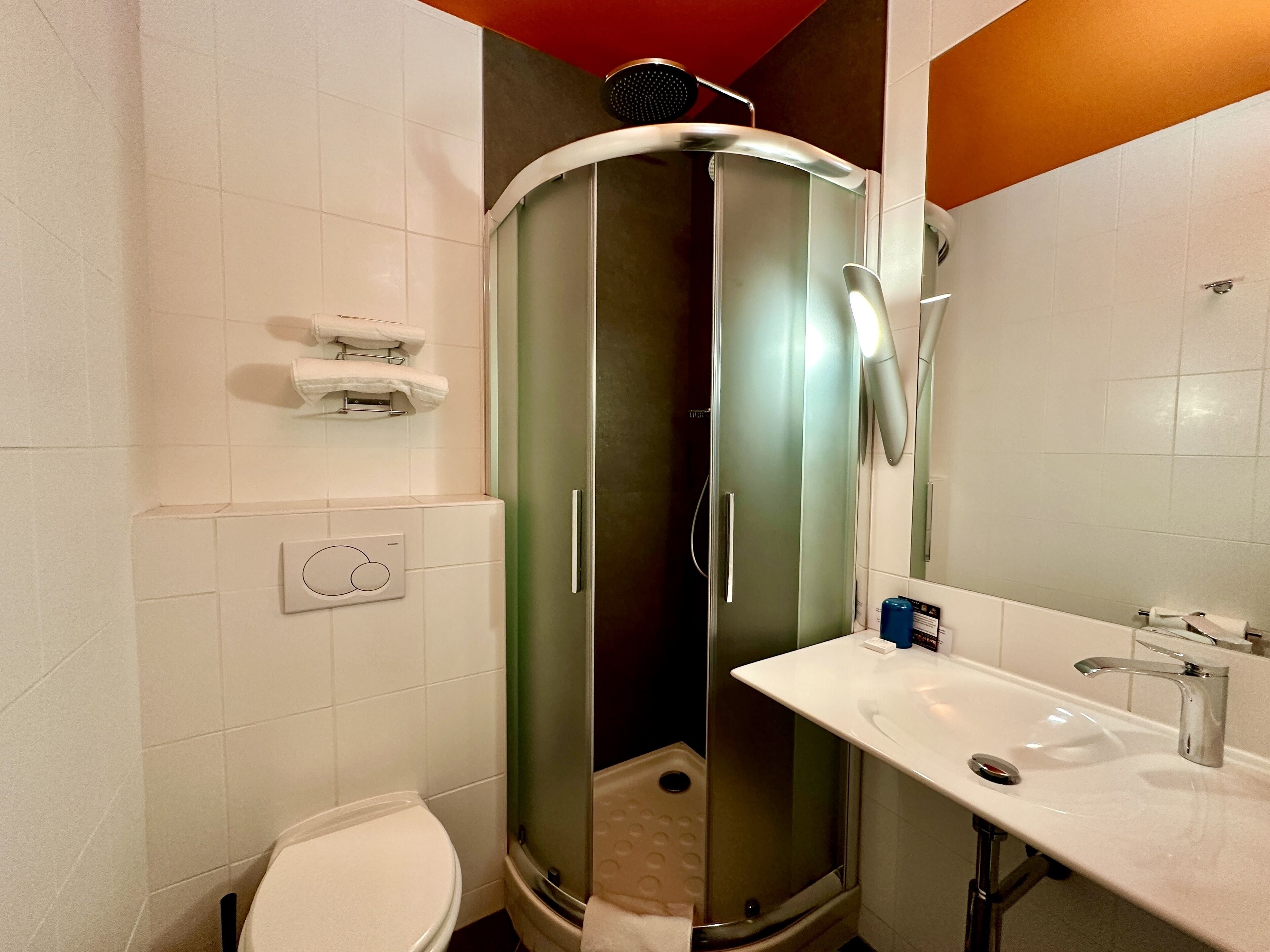 Un baño con cabina de ducha, inodoro y lavamanos.