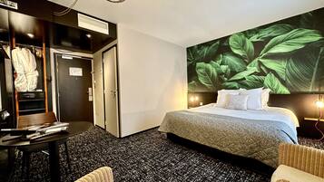 A hotel room with a bed, a desk, a chair, and a wardrobe.