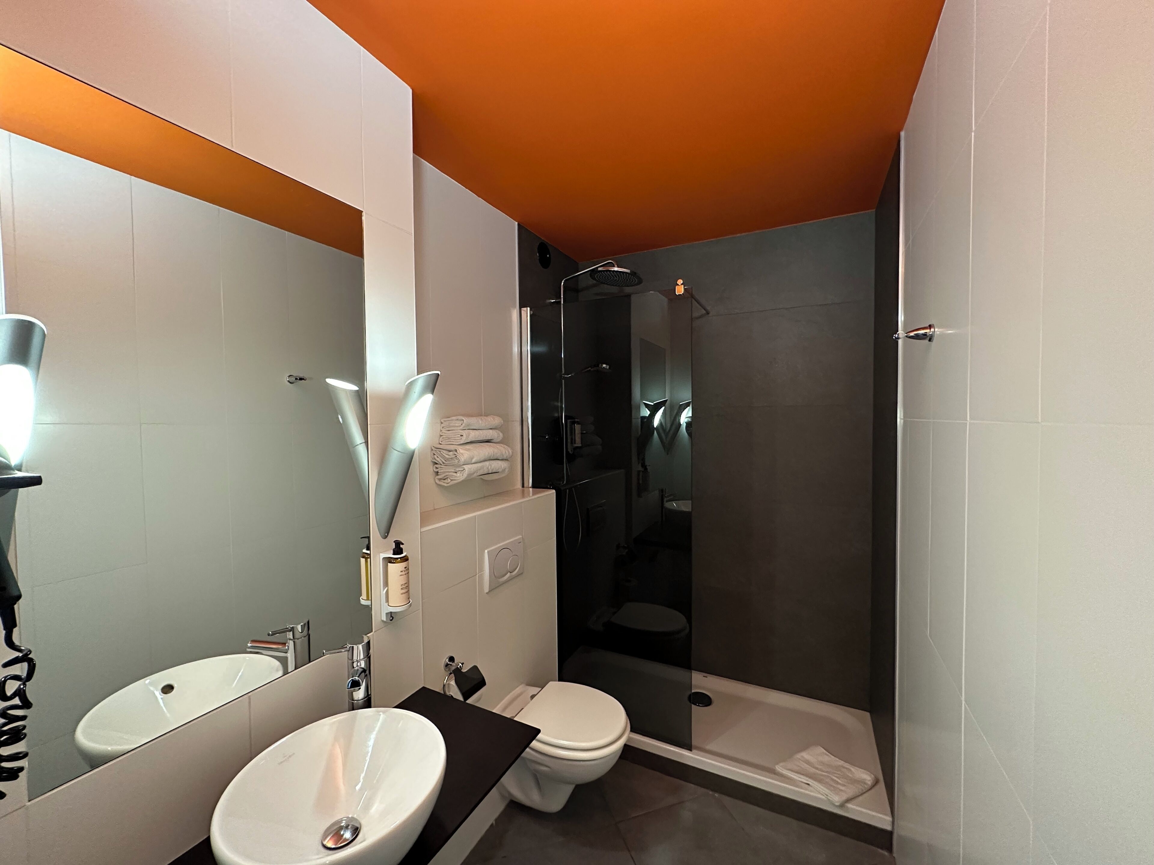 A modern bathroom with two sinks, a toilet, and a walk-in shower.