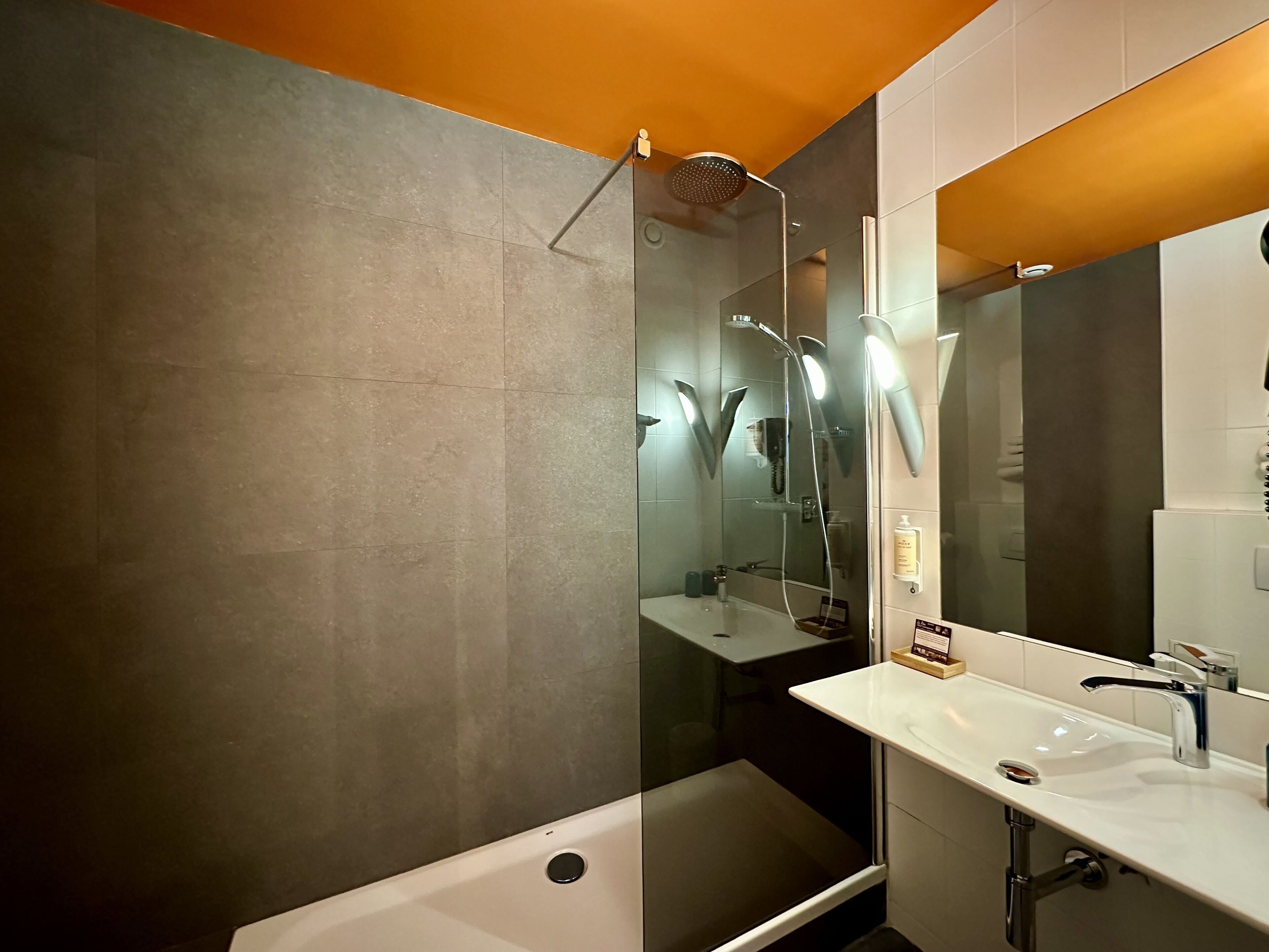 A modern bathroom with a bathtub, a large mirror, and a shower area.