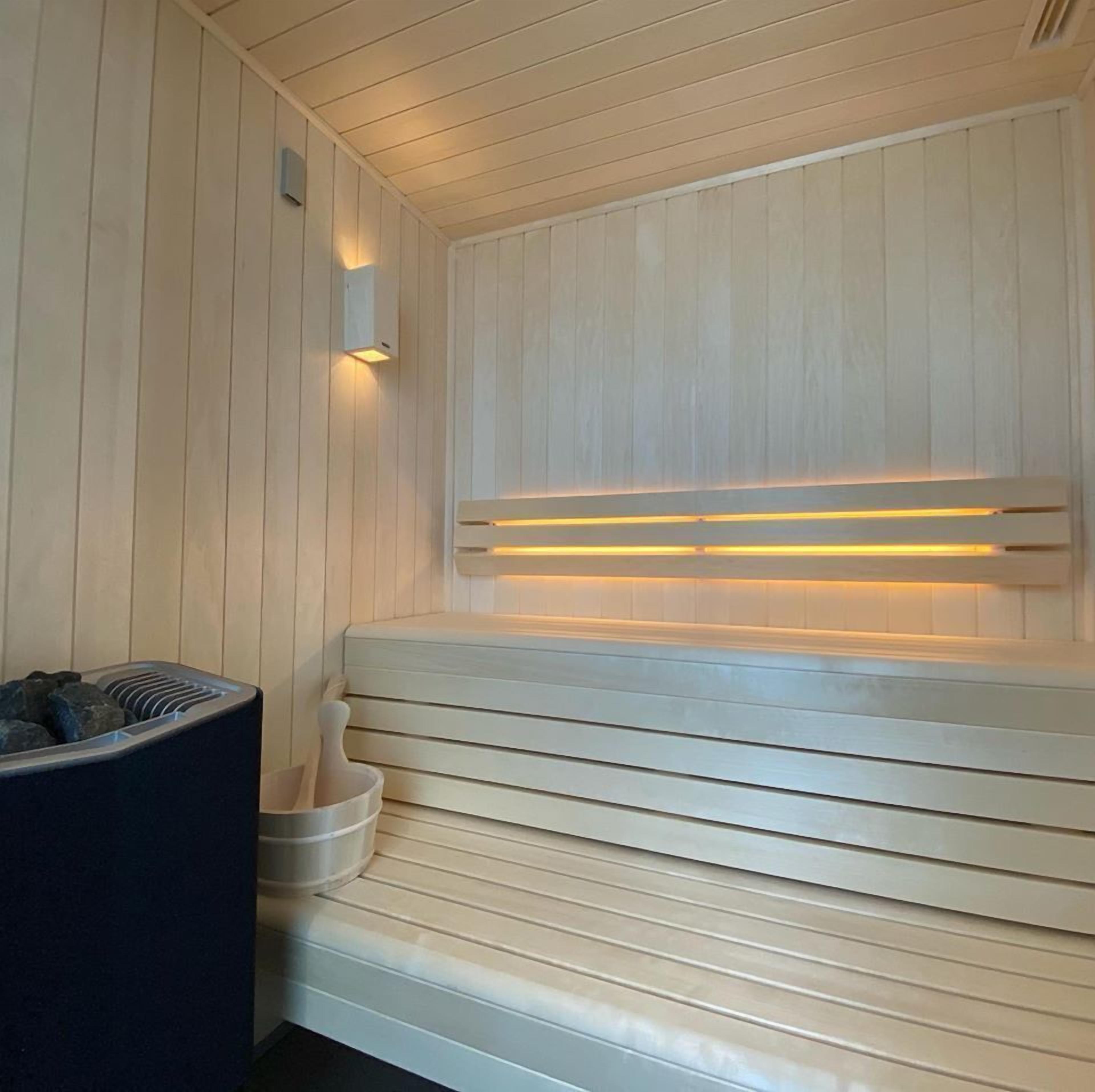 Un sauna avec des bancs en bois et un bassin en pierre.