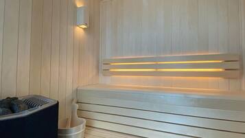 Un sauna avec des bancs en bois et un bassin en pierre.