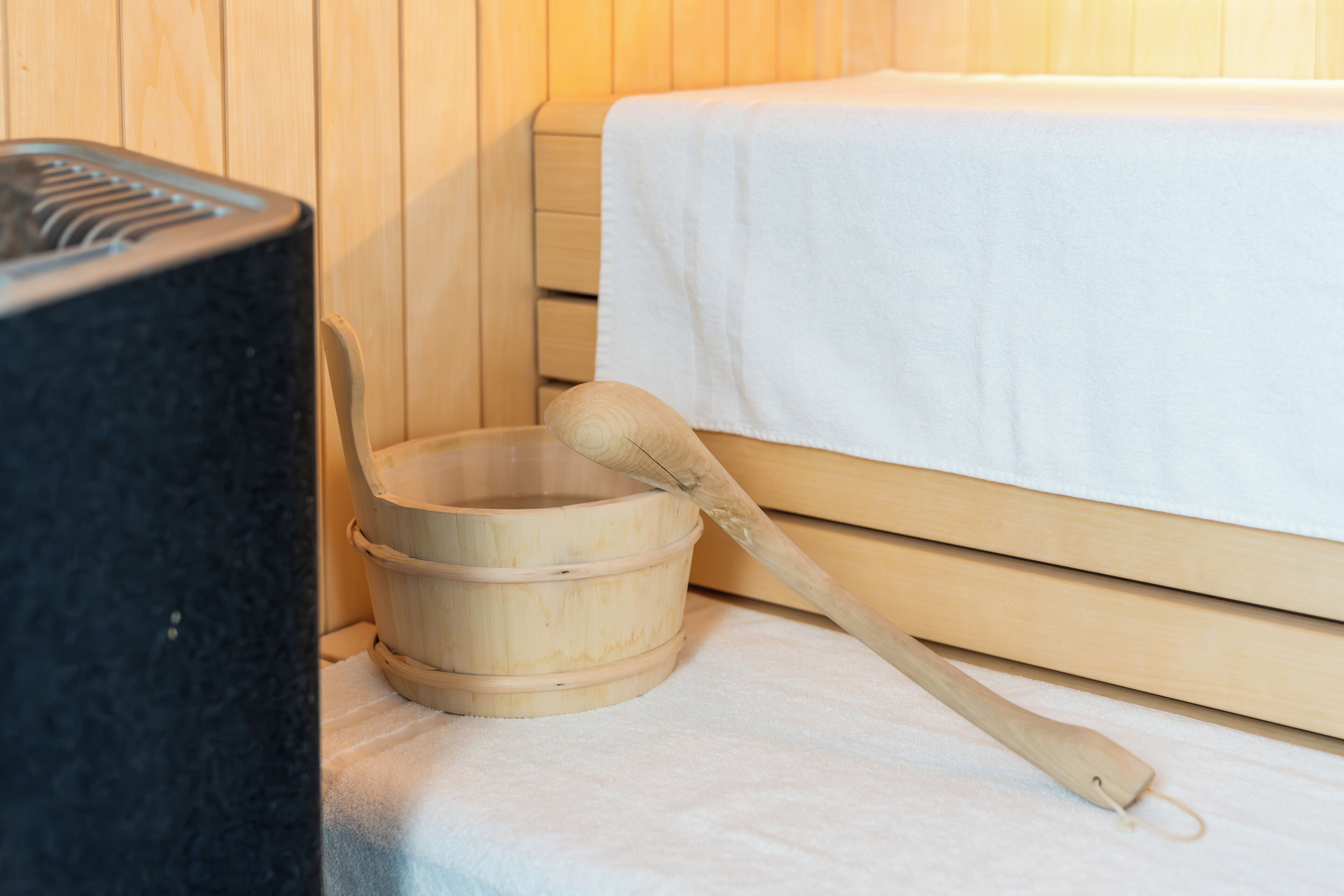 A wooden sauna with a large wooden bucket and a wooden mallet.