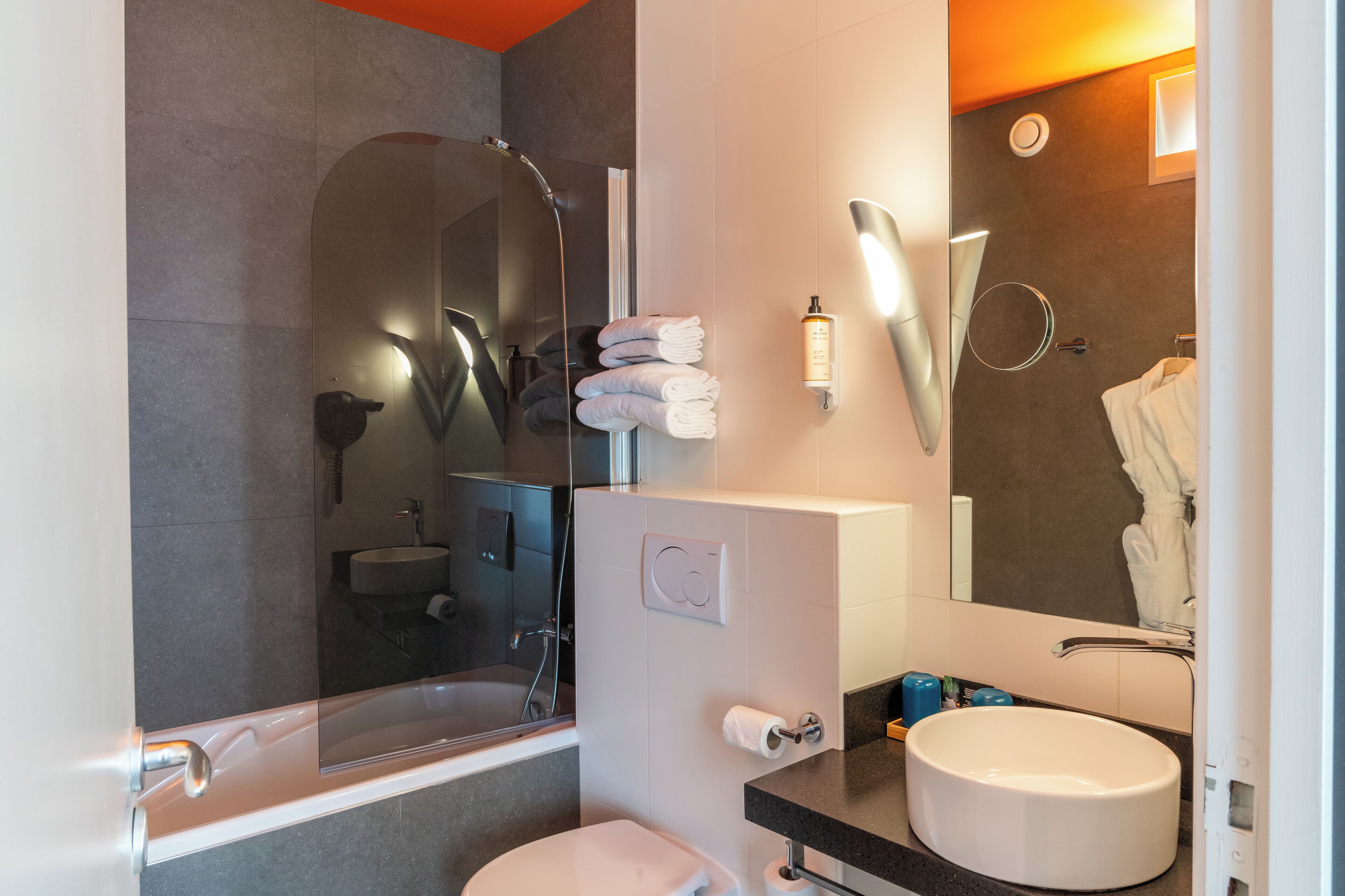 A modern bathroom with a bathtub, toilet, sink, and a large mirror.