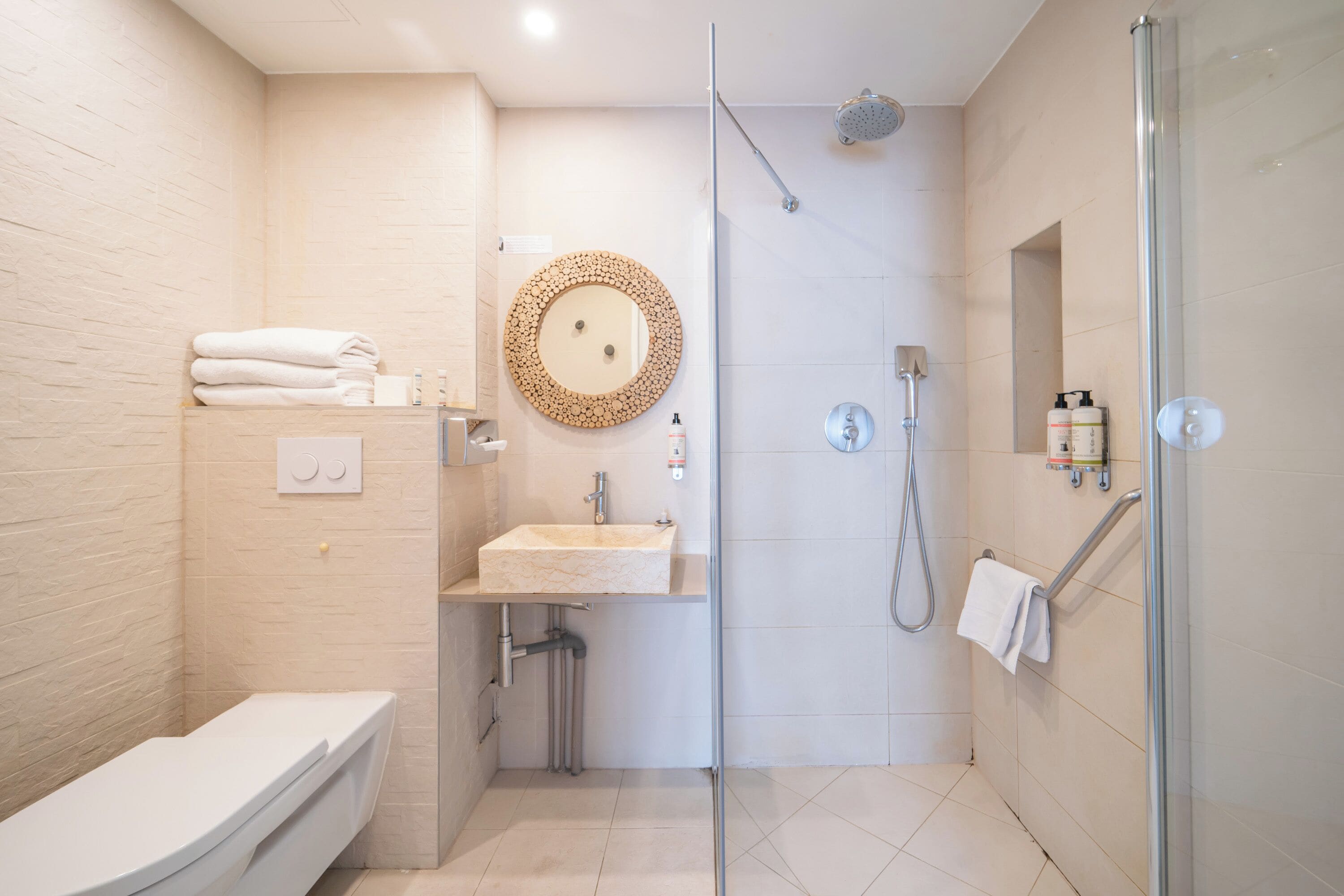 A modern bathroom with a glass-enclosed shower, a sink with a wooden countertop, and a toilet.