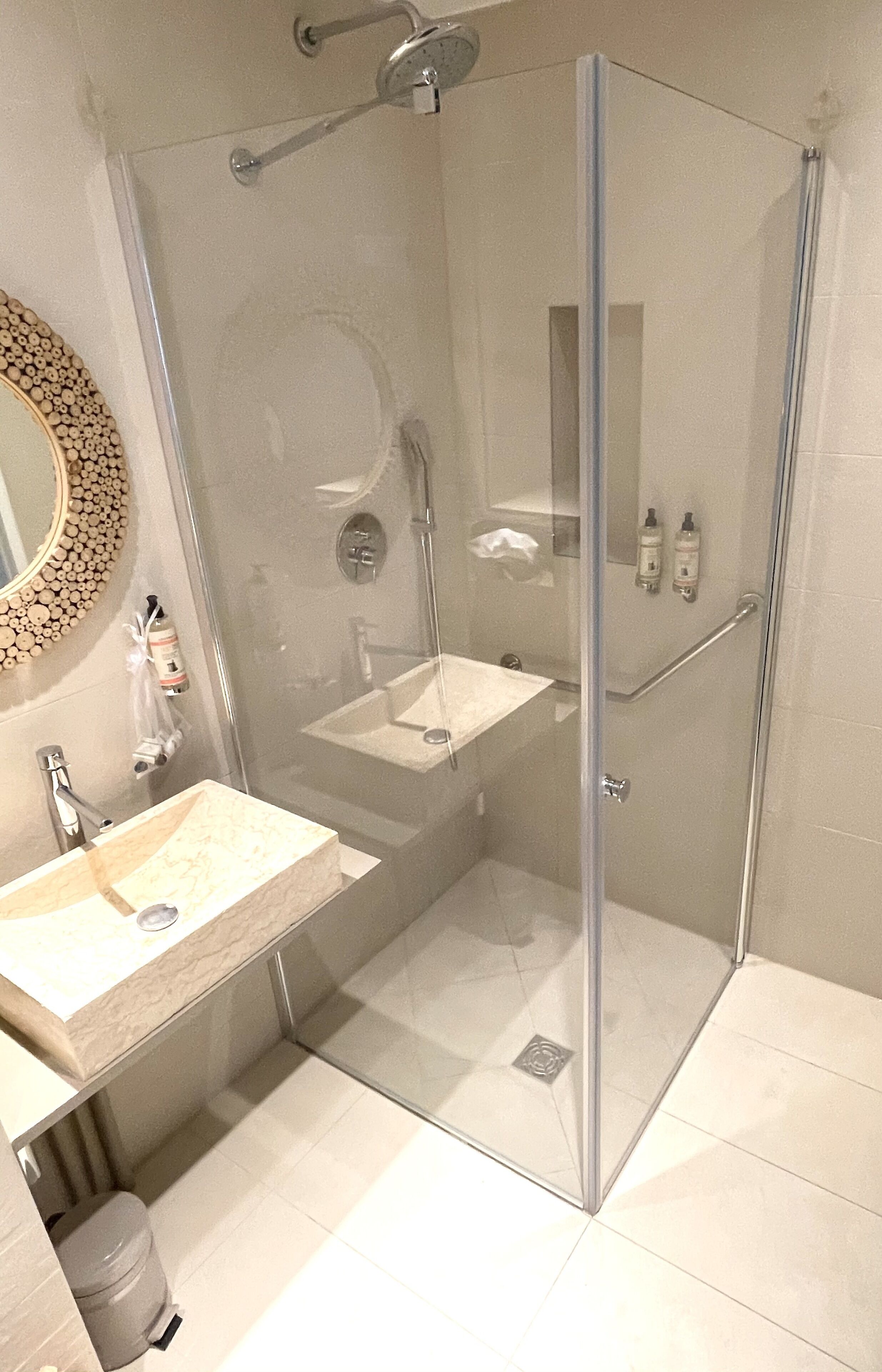 A modern bathroom with a glass-enclosed shower, a vanity with a sink, and a mirror.