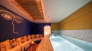 A spa area with a long bench, a tiled pool, and a wall with a geometric design. - La Finca Hôtel & Spa (Paris)