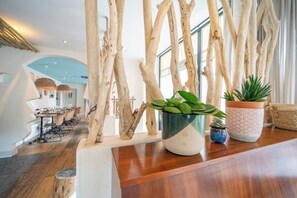 A reception area with a wooden reception desk, potted plants, and a view of the dining area. - La Finca Hôtel  (Paris)