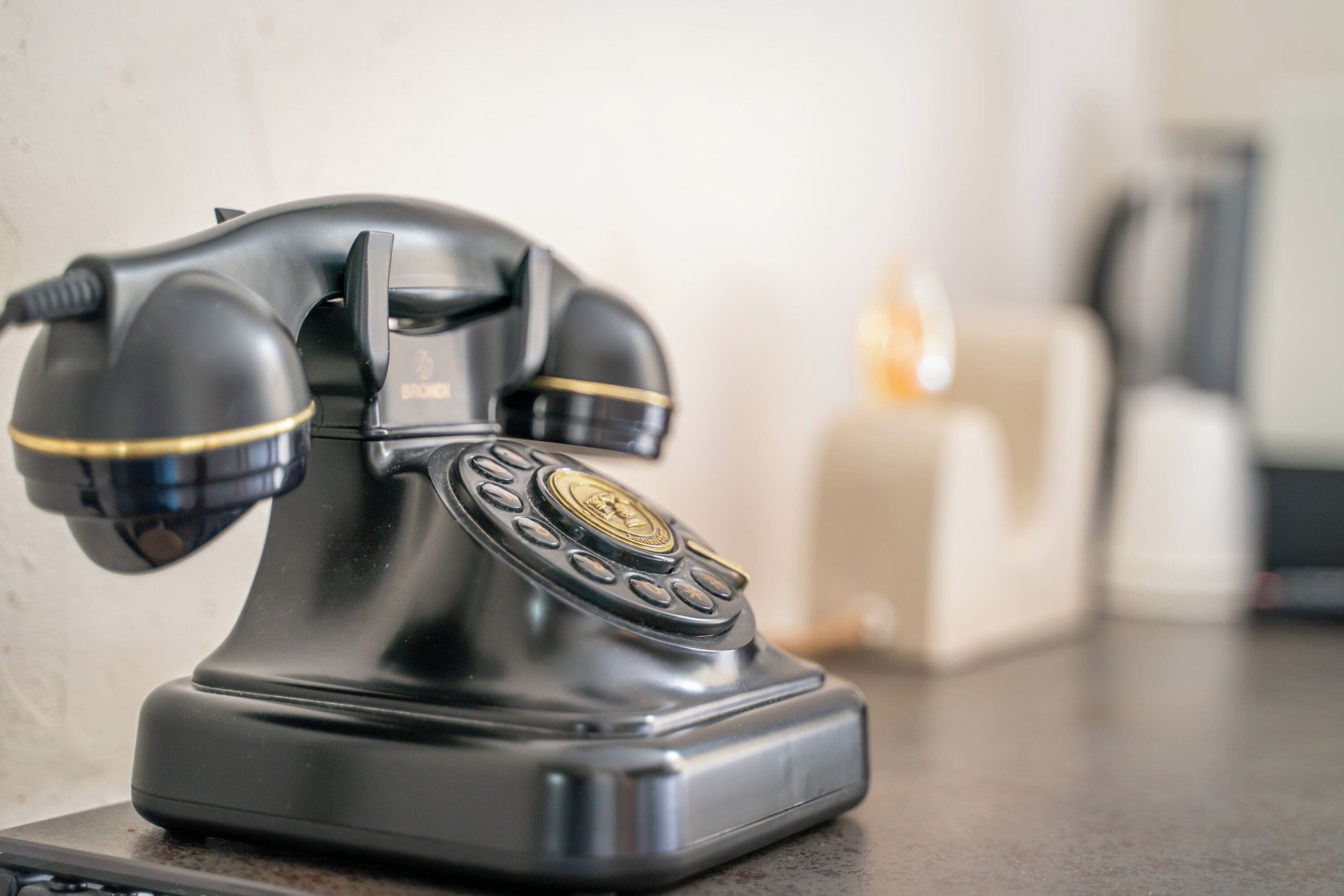 A vintage black rotary telephone on a table.