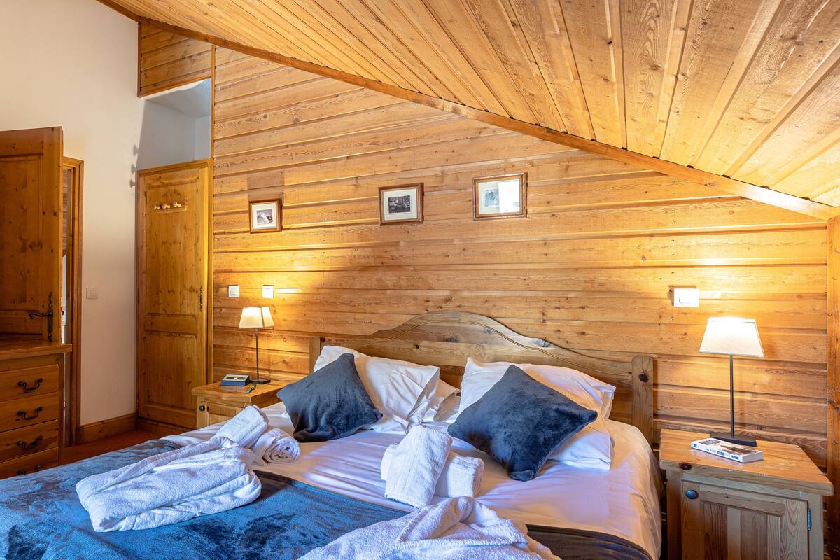 Un dormitorio con paneles de madera, una cama, mesitas de noche y un armario.
