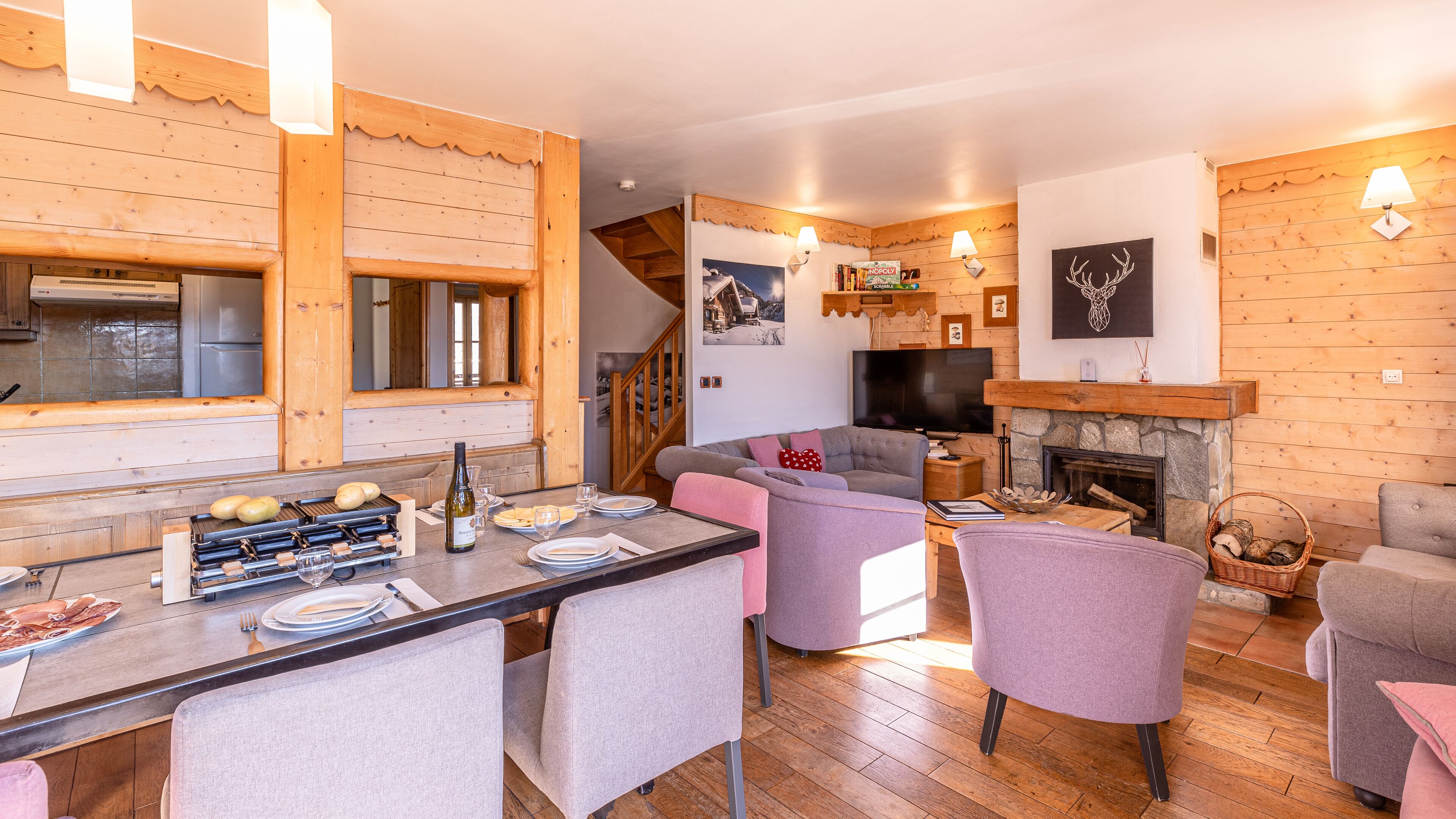 A cozy cabin interior with a dining area, a sofa, a fireplace, and a TV.