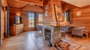 A wooden cabin interior with a fireplace, a television, and a dining area. - Madame Vacances Les Chalets de l'Altiport (Huez)