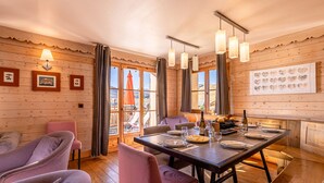 A dining area with wooden walls, a table set for two, and a view of the outdoors. - Madame Vacances Les Chalets de l'Altiport (Huez)