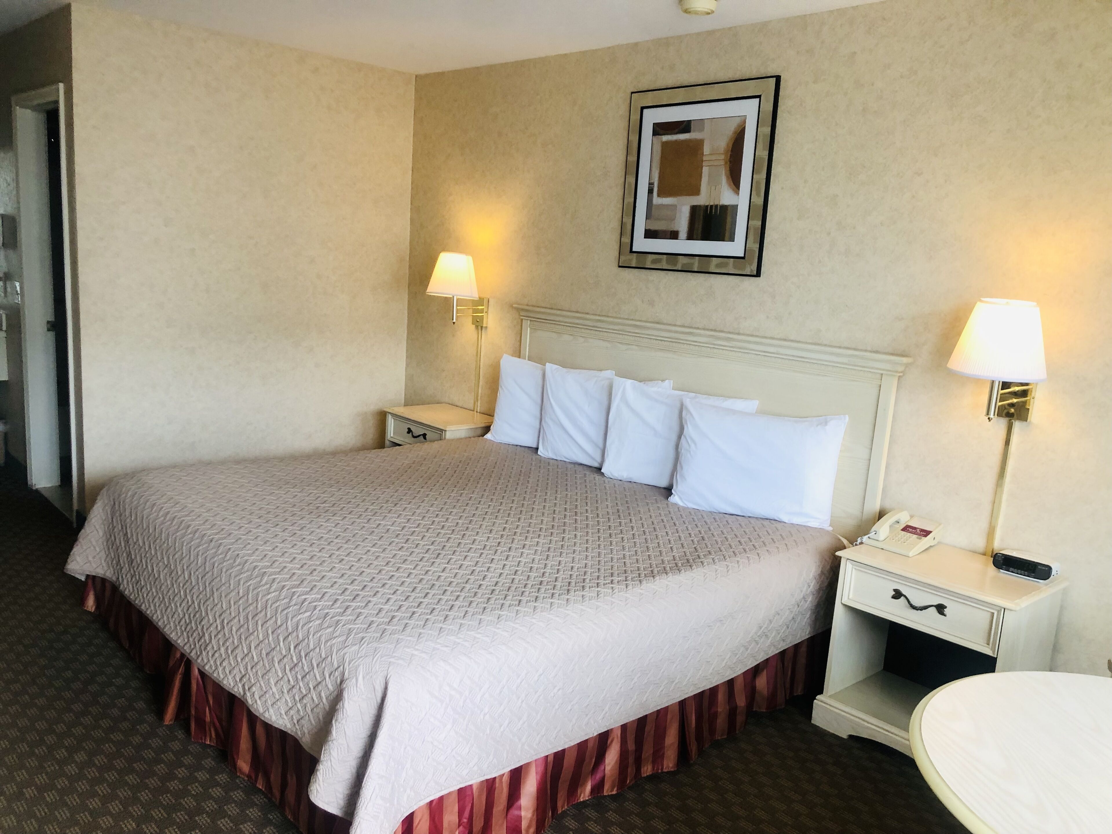 Een hotelkamer met een groot bed, twee nachtkastjes, een spiegel en een wandlamp.