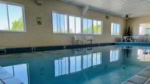 An indoor swimming pool with clear water, surrounded by tiled walls and windows. - Court Plaza Inn & Suites (Mackinaw City)