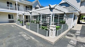 A covered outdoor seating area with planters and a pergola. - Court Plaza Inn & Suites (Mackinaw City)