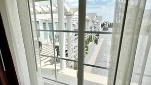 A window with a view of a covered outdoor area with white columns and a street. - Court Plaza Inn & Suites (Mackinaw City)