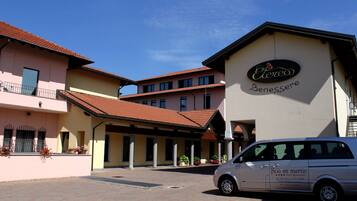 A hotel with a sign reading "Eterco Benessere" and a van parked in front.
