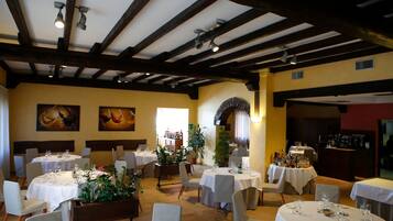 A restaurant with round tables, chairs, and a bar area.
