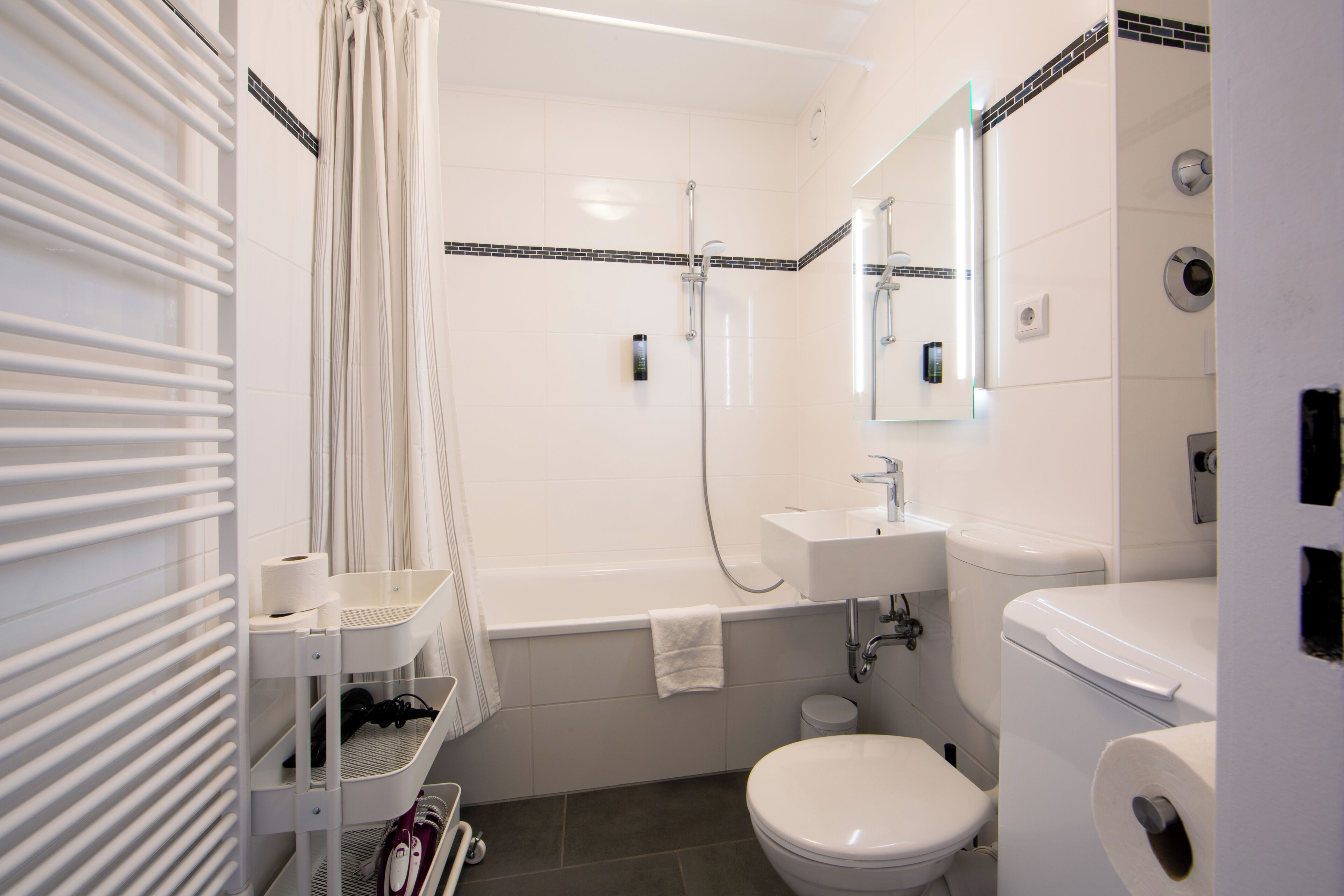 Une salle de bain équipée d’une baignoire, de toilettes, d’un lavabo et d’un porte-serviettes.