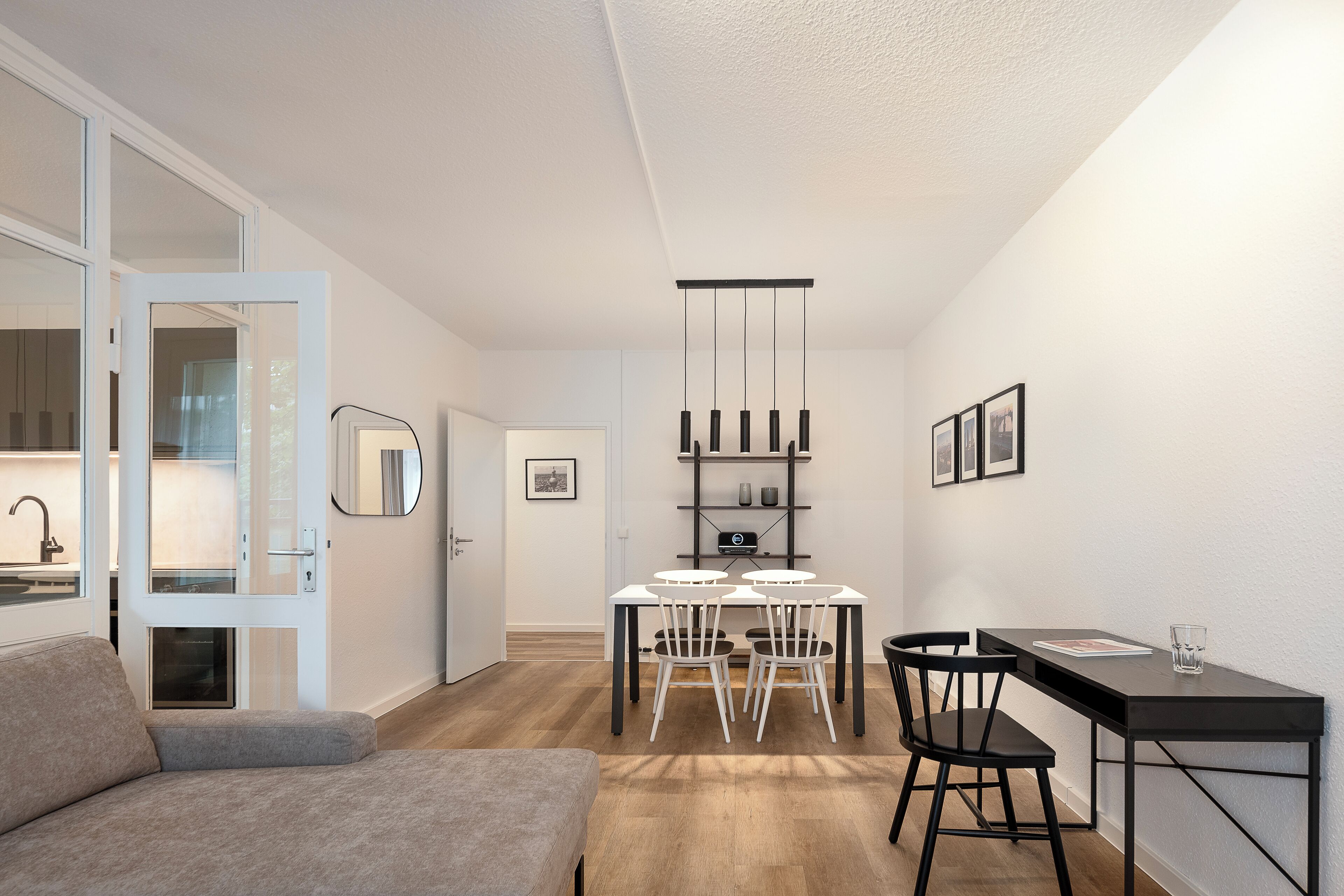 Un espacio habitable moderno y compacto con comedor, sofá y una pequeña cocina.